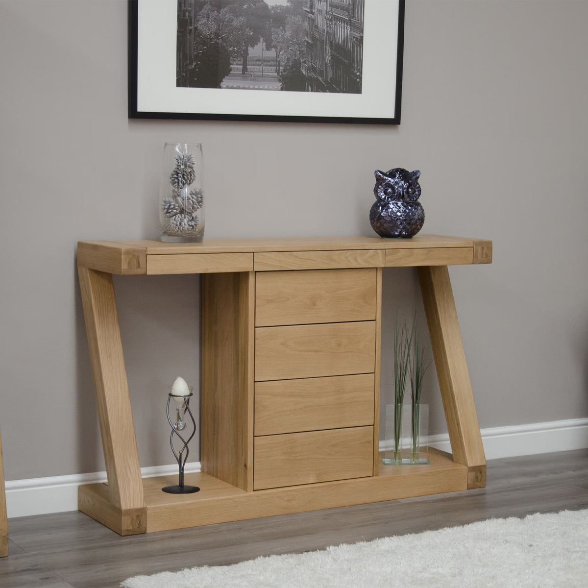 Oak console table with four drawers, decorative vase, and owl ornament against grey wall