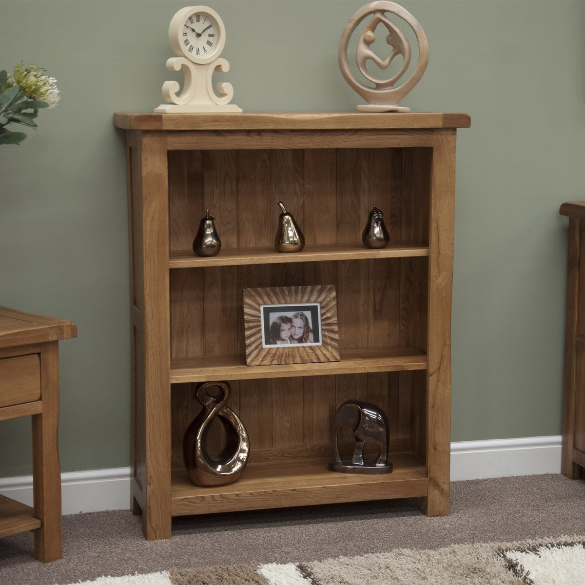 Oak bookcase with three shelves featuring decorative ornaments and photo frame