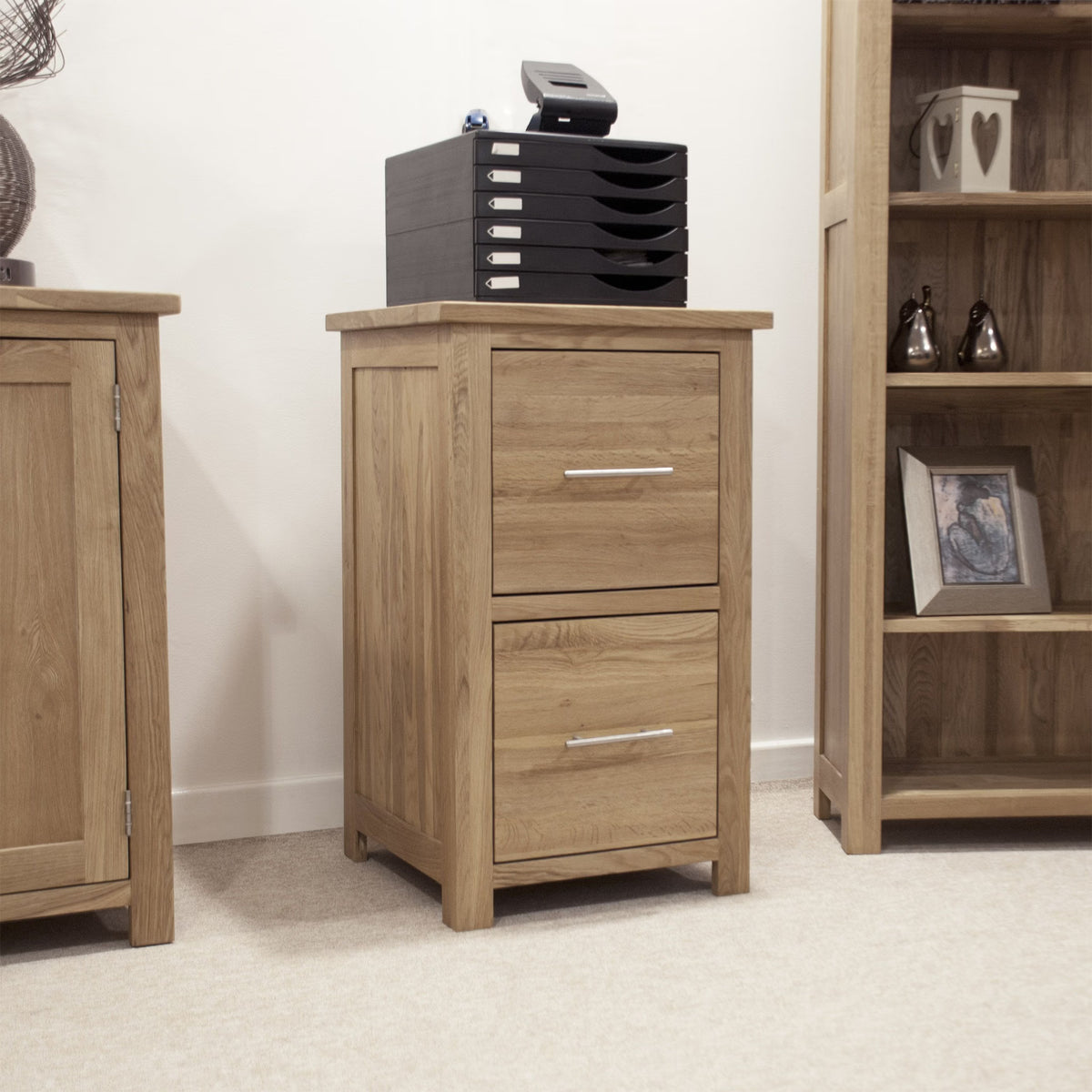 Oak filing cabinet with two drawers and metal handles in a home office setting
