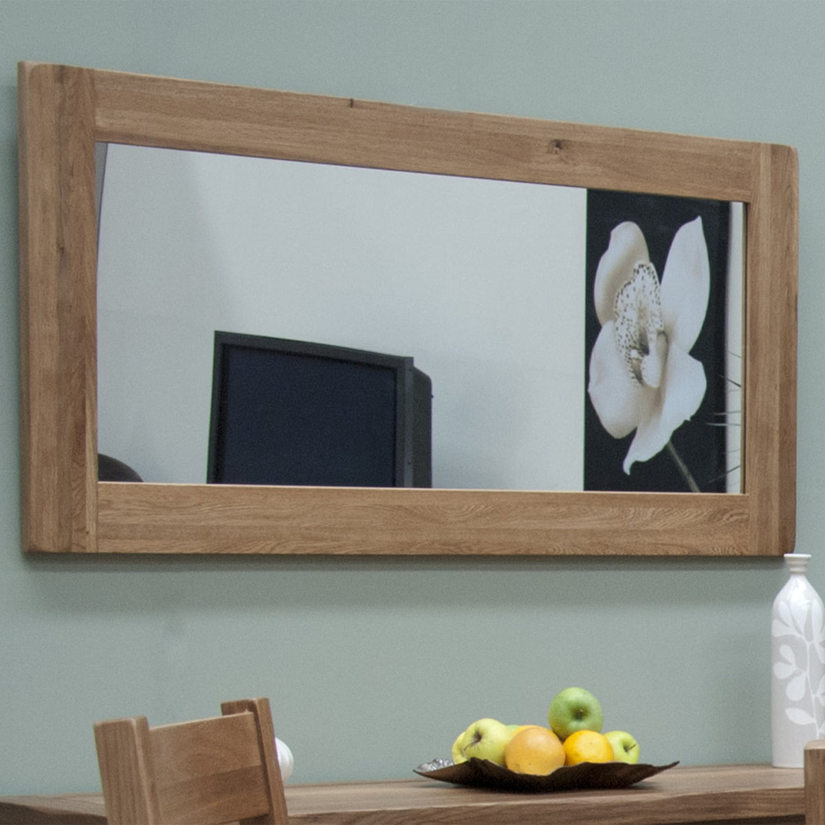 Rectangular wooden frame wall mirror above dining table with fruit bowl and vase