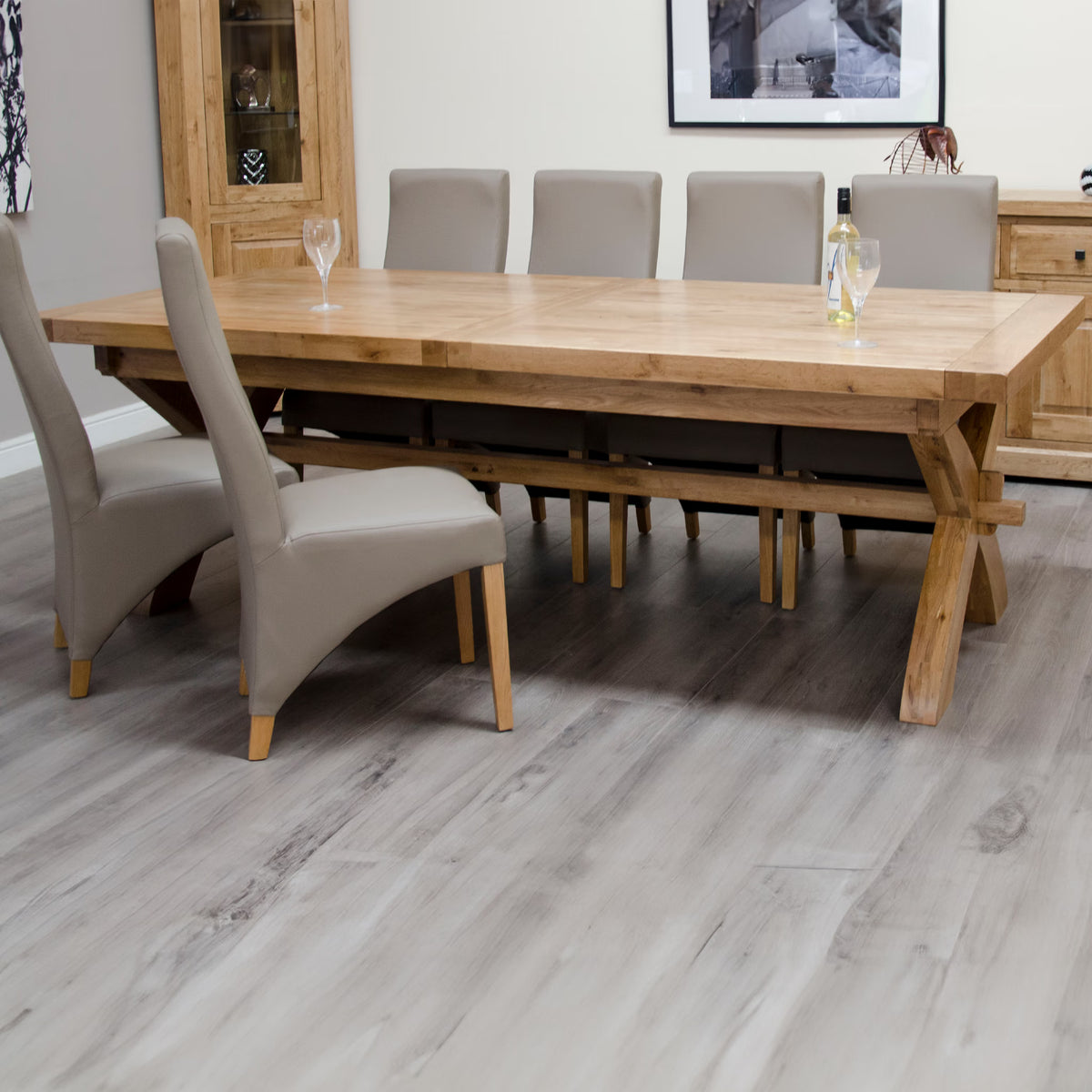 Oak dining table with six taupe upholstered chairs in modern dining room setting