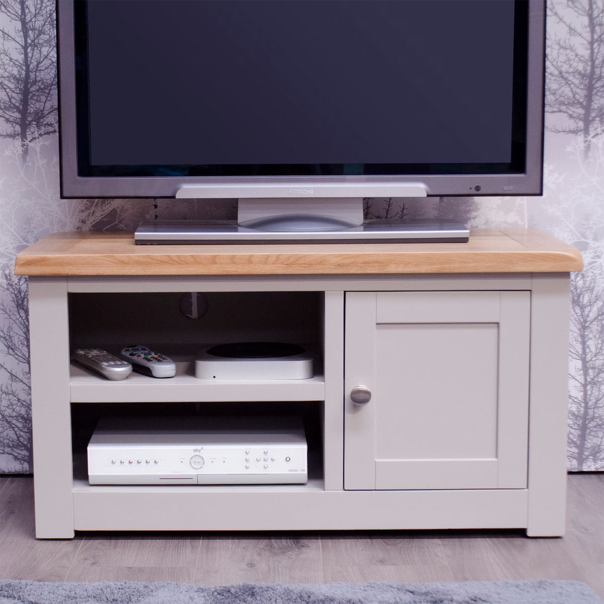 Grey wooden TV unit with oak top, open shelves and cabinet, remote controls on shelf