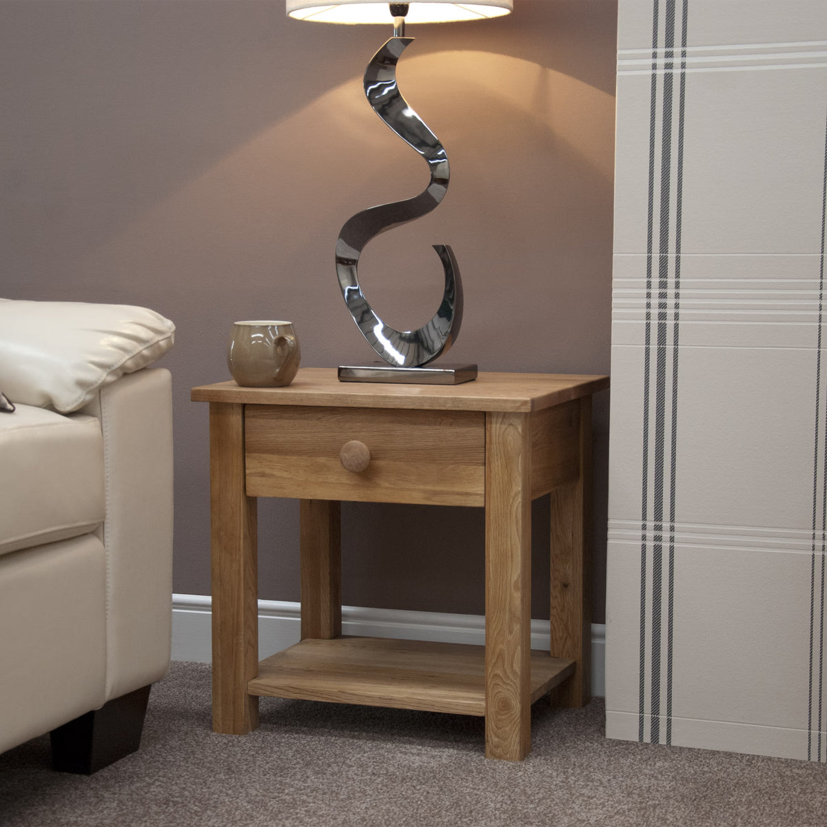 Oak side table with drawer and shelf next to sofa, lamp and mug placed on top