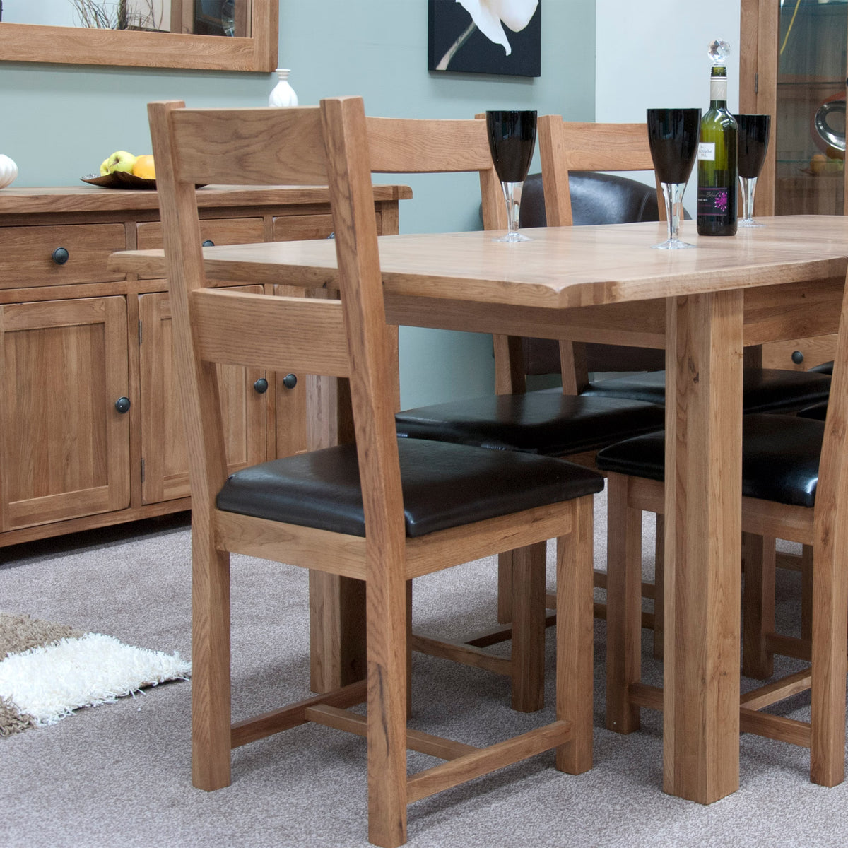 Solid oak dining table set with black cushioned chairs in a modern dining room