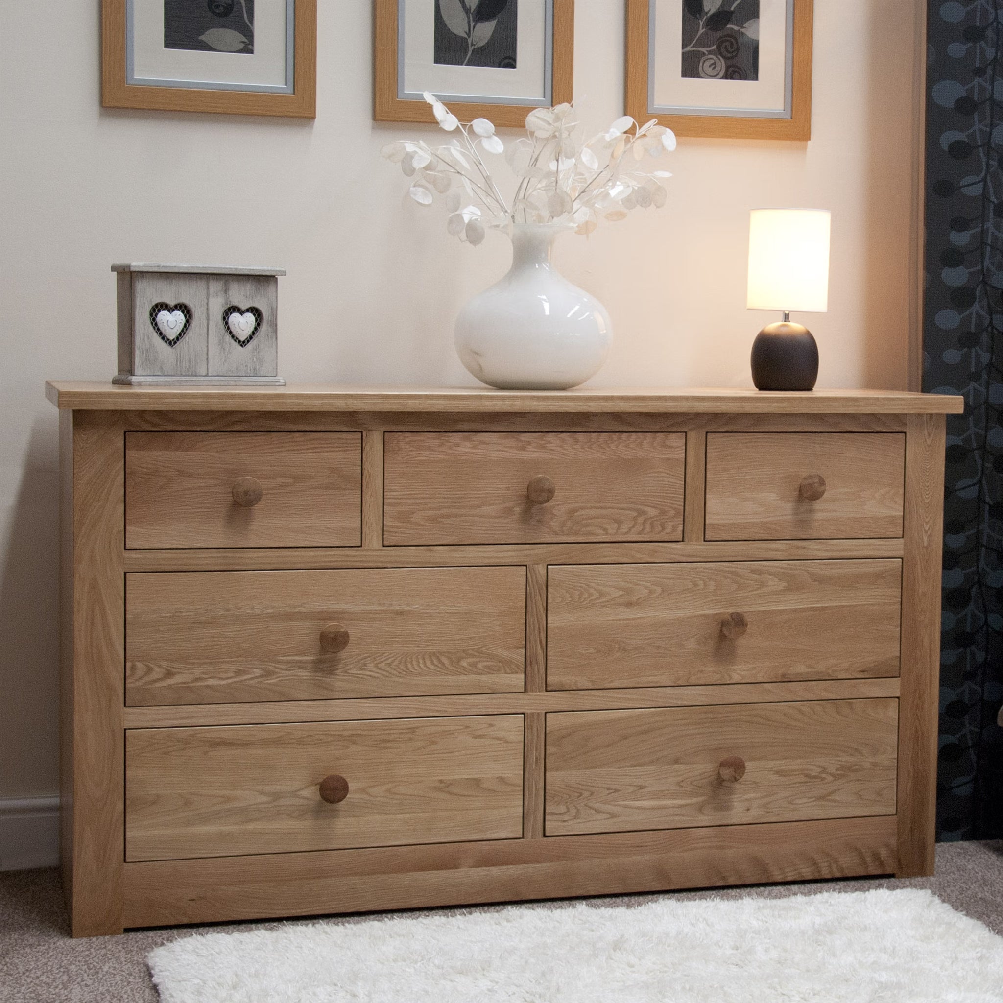 Oak chest of drawers with seven storage drawers in bedroom setting with decor items