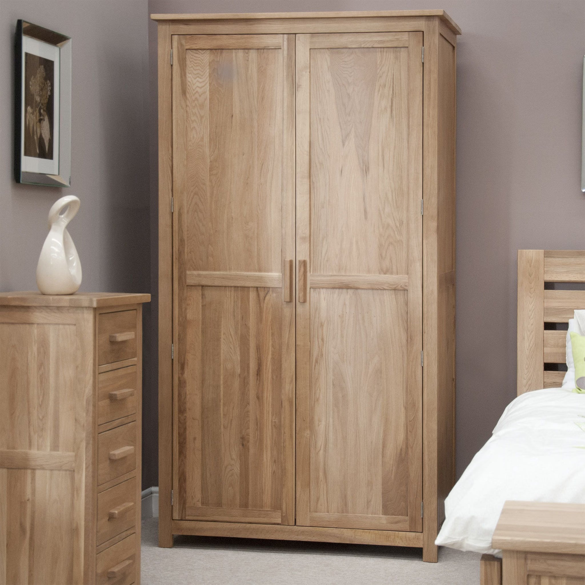 Oak wardrobe with double doors in a modern bedroom, matching oak chest and bed visible