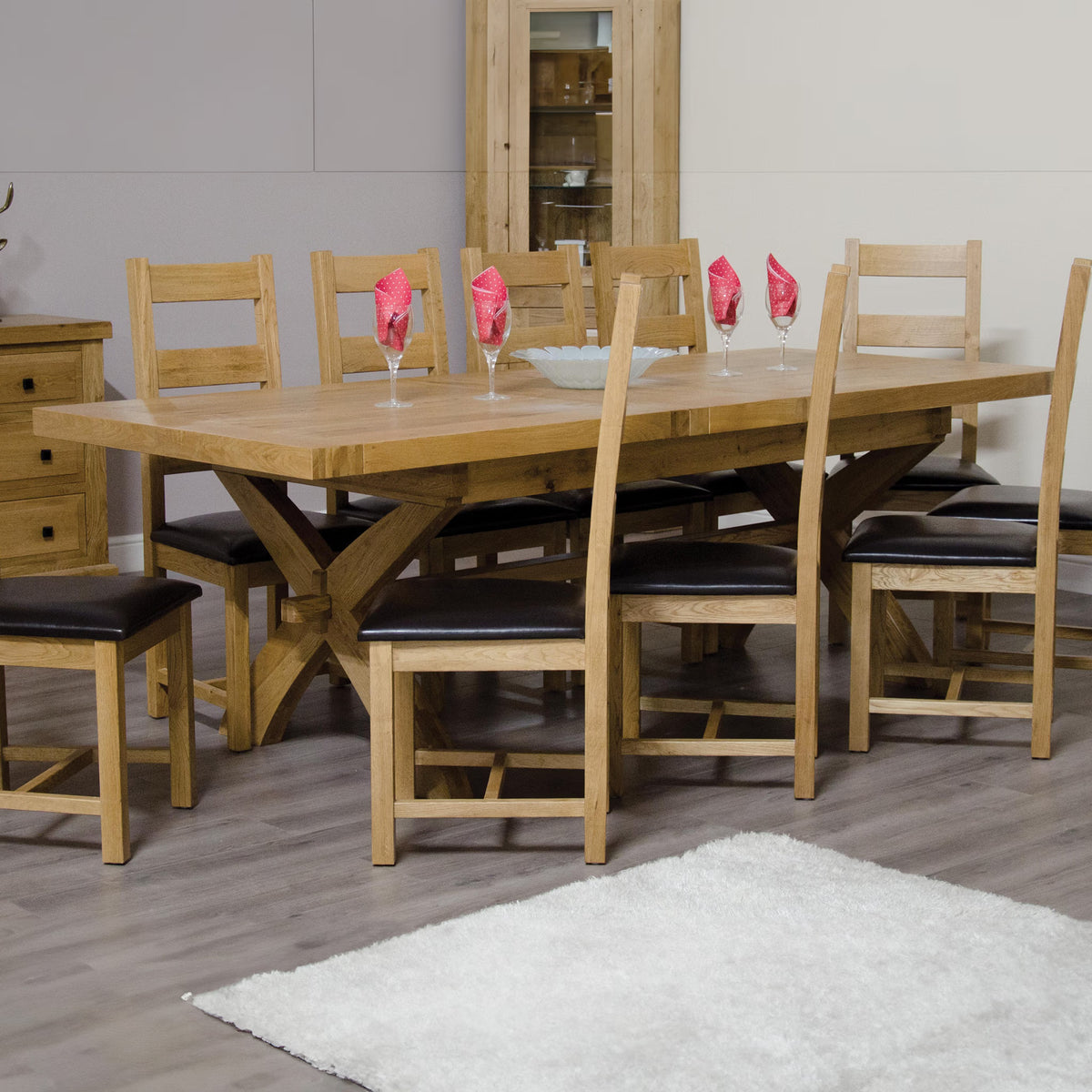 Oak dining table set with eight chairs and dark cushions on wood floor