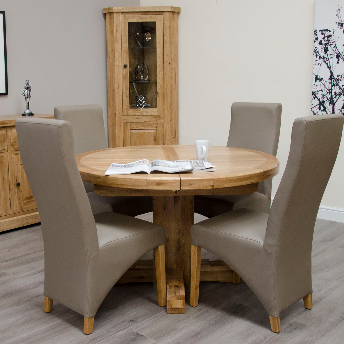 Oak round dining table with beige upholstered chairs in modern dining room