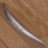 Chrome drawer handle on light oak wood furniture close-up