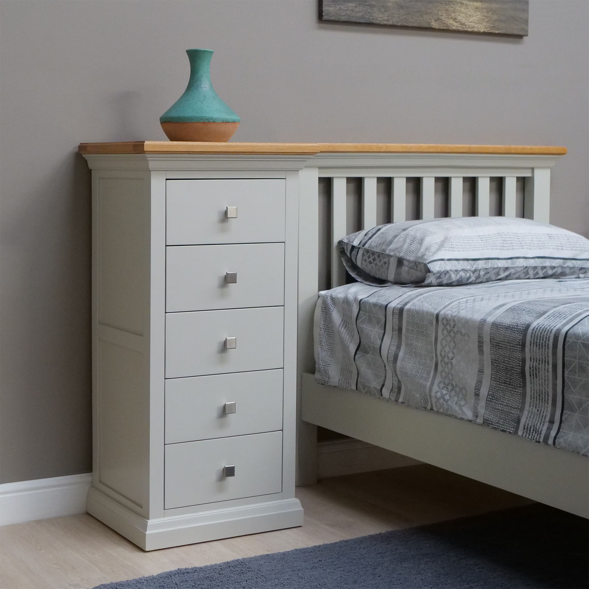 Cream bedside chest of drawers with oak top next to slatted bed frame in modern bedroom