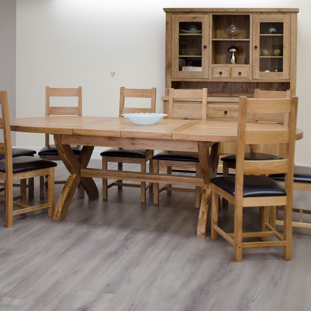 Oak dining table with six chairs and glass-fronted oak display cabinet on wood flooring
