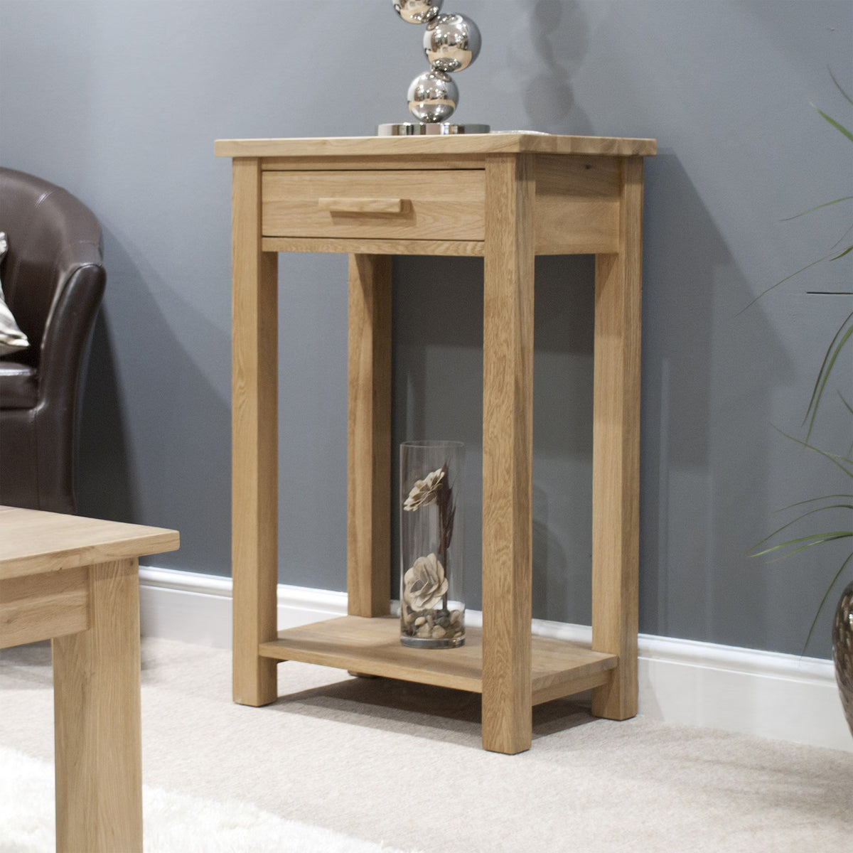 Oak console table with drawer and lower shelf against grey wall in living room