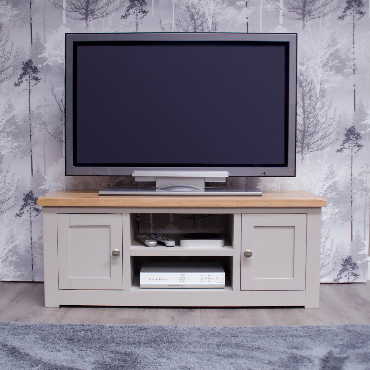 Grey wooden TV unit with oak top, storage shelves, and closed cupboards in living room setting