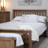 Wooden bed frame with white bedding and matching bedside cabinet in cosy bedroom setting