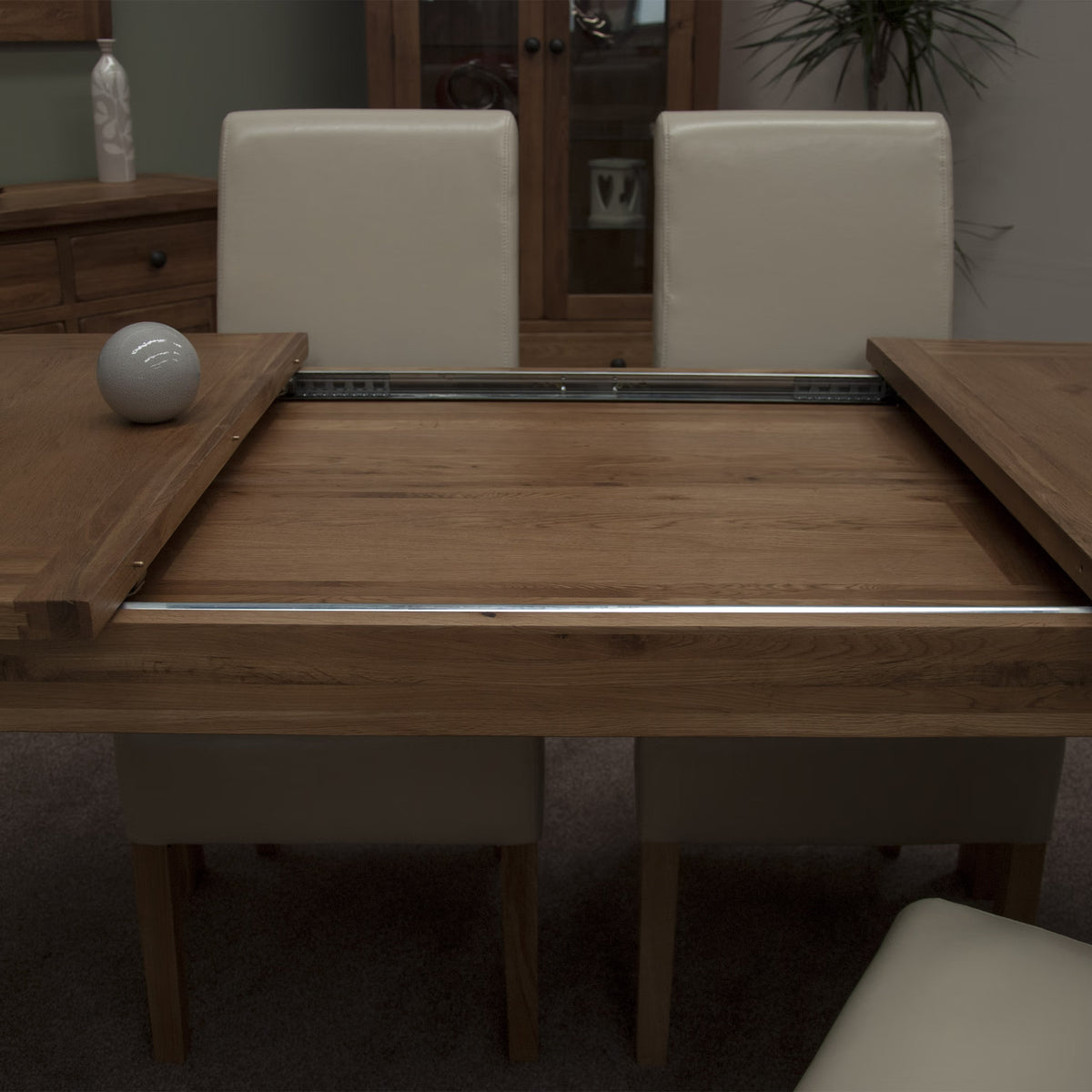 Oak extending dining table with cream chairs showing smooth slide-out mechanism