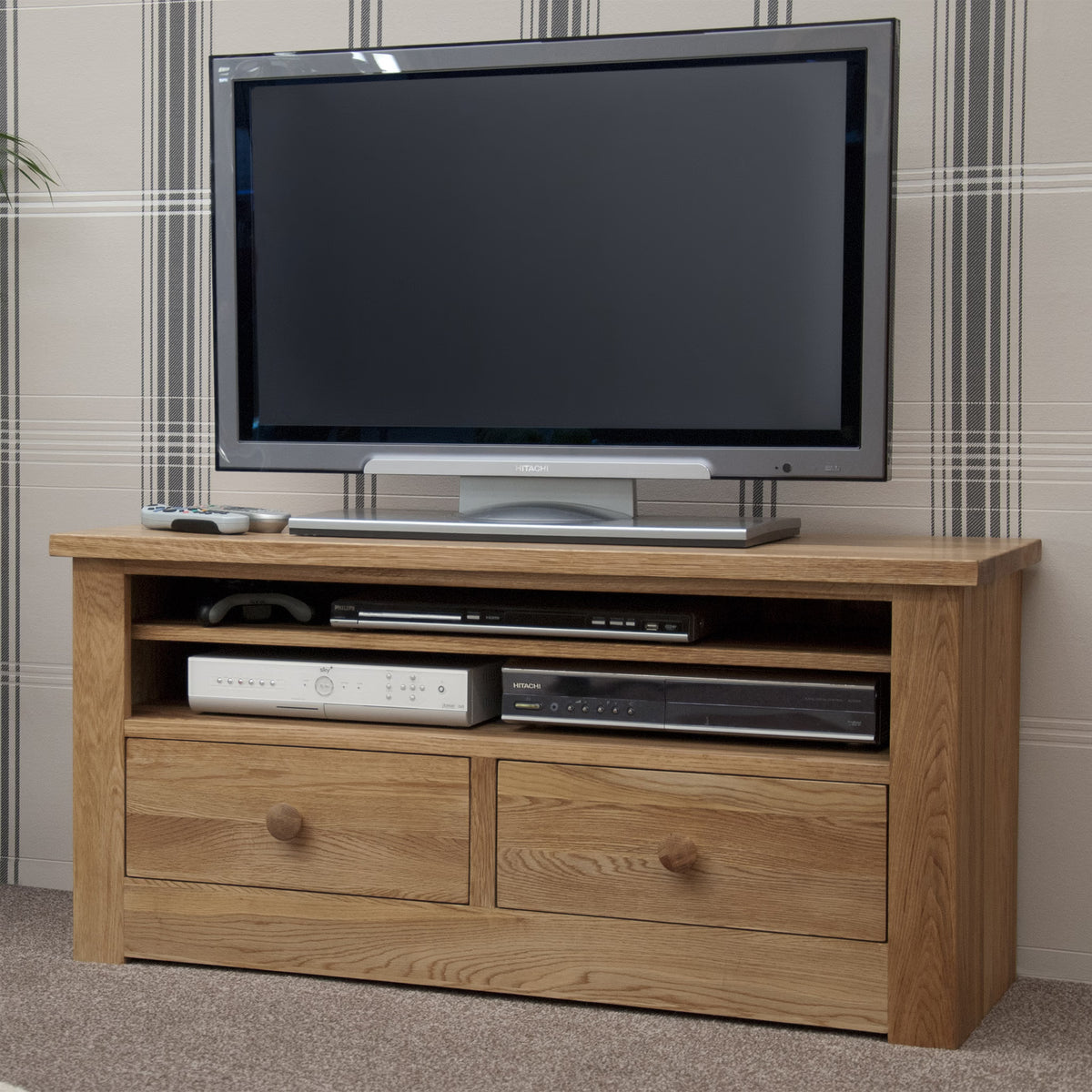 Oak TV unit with two drawers and open shelves holding electronics in living room setting