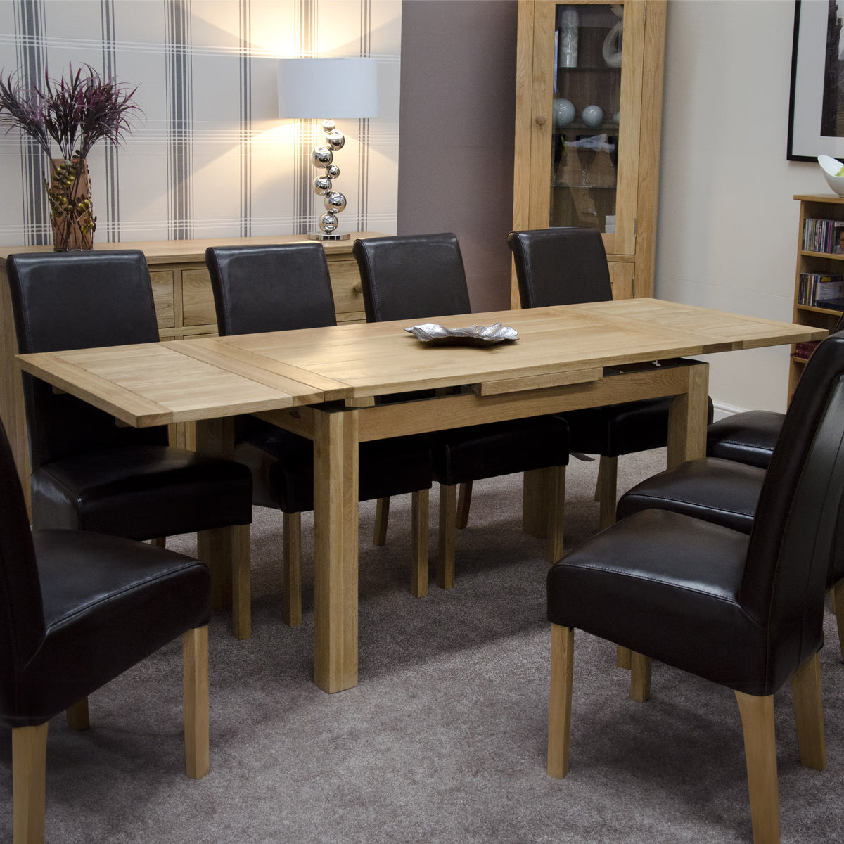 Oak dining table with black leather chairs in a modern dining room setting