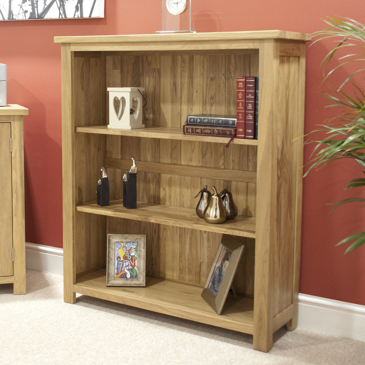 Oak wooden bookcase with shelves displaying books, decor, and framed photos in living room