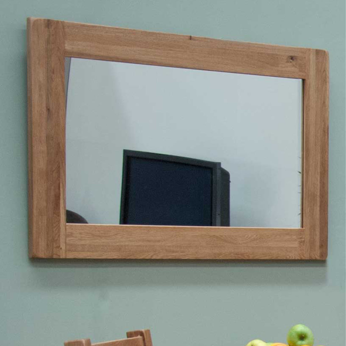 Rectangular wooden wall mirror with natural oak frame on light green painted wall
