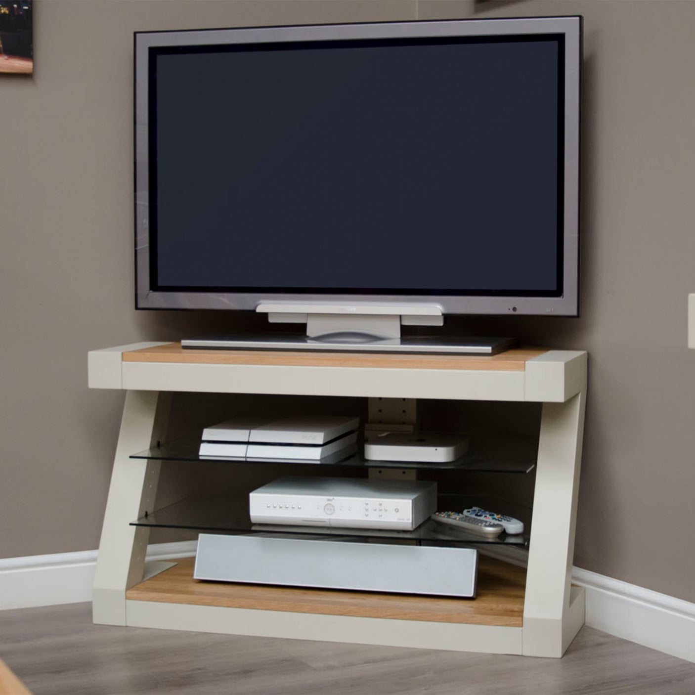 Modern TV unit with wood top, two glass shelves and media devices in a corner living room