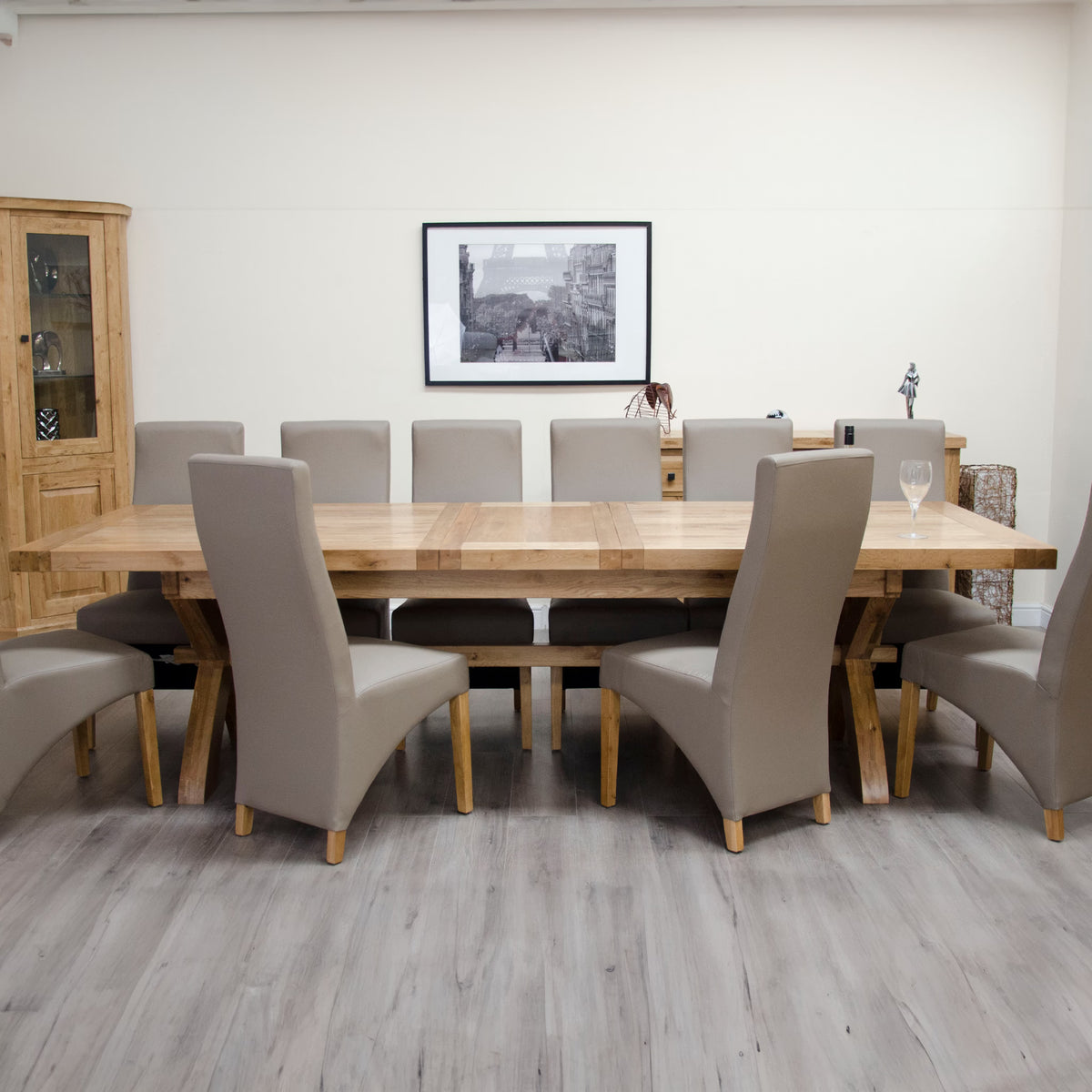 Rectangular wooden dining table with eight beige upholstered chairs in modern dining room