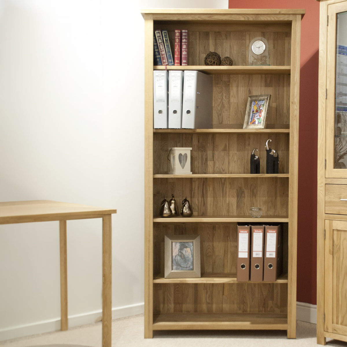 Oak bookcase with shelves holding books, files, decor and framed photos in modern office