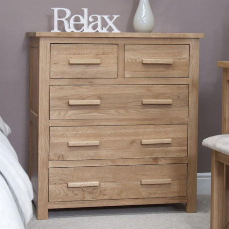 Natural oak chest of drawers with four drawers and wooden handles in bedroom setting