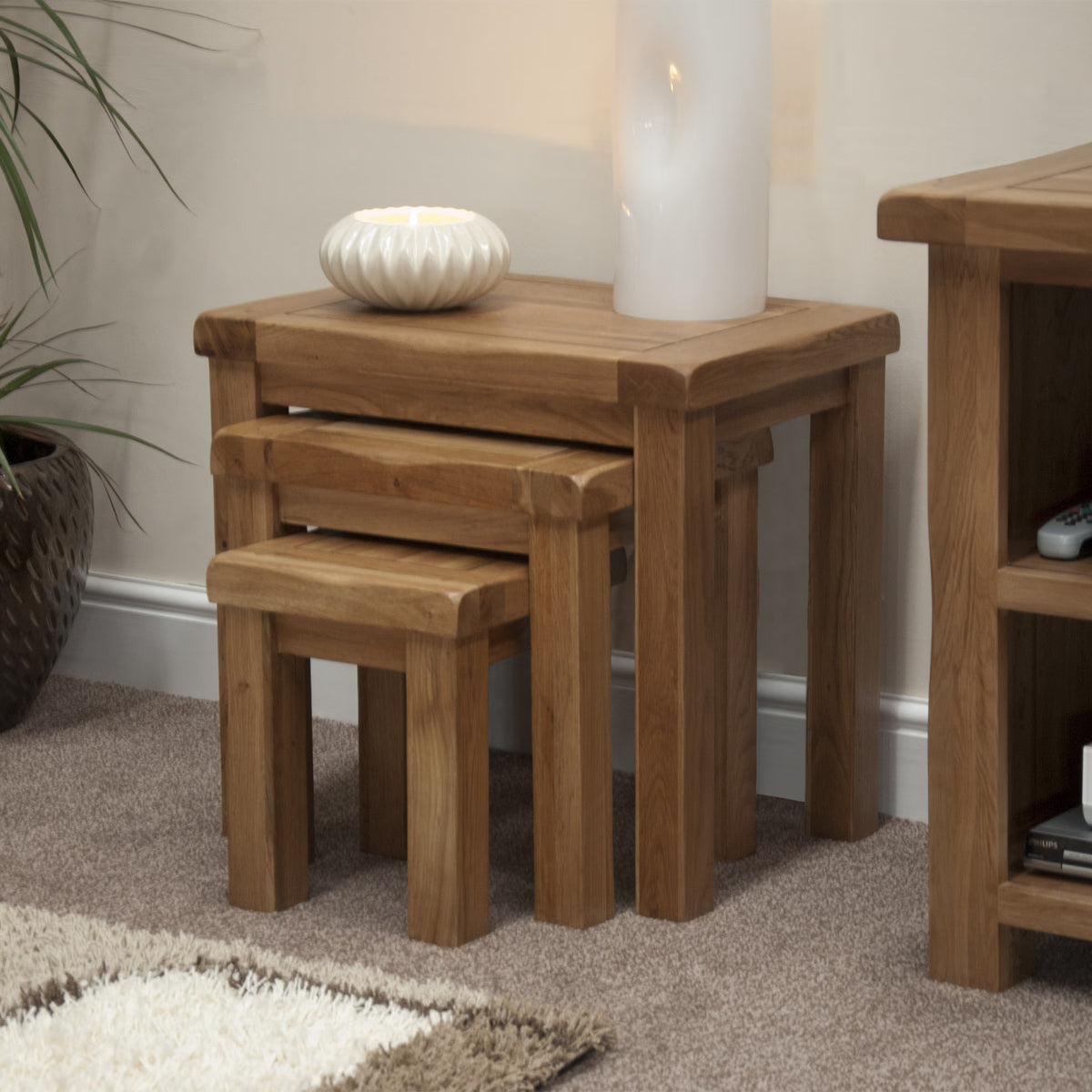 Oak nesting tables set with decorative lamp and bowl in living room