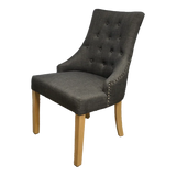 Dark grey upholstered dining chair with button tufting and light wood legs