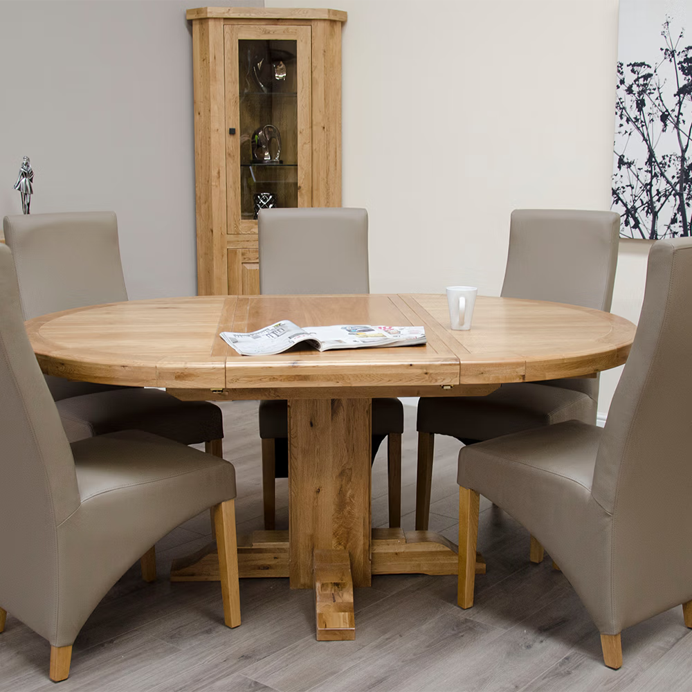 Round oak dining table with six beige chairs and display cabinet in modern dining room