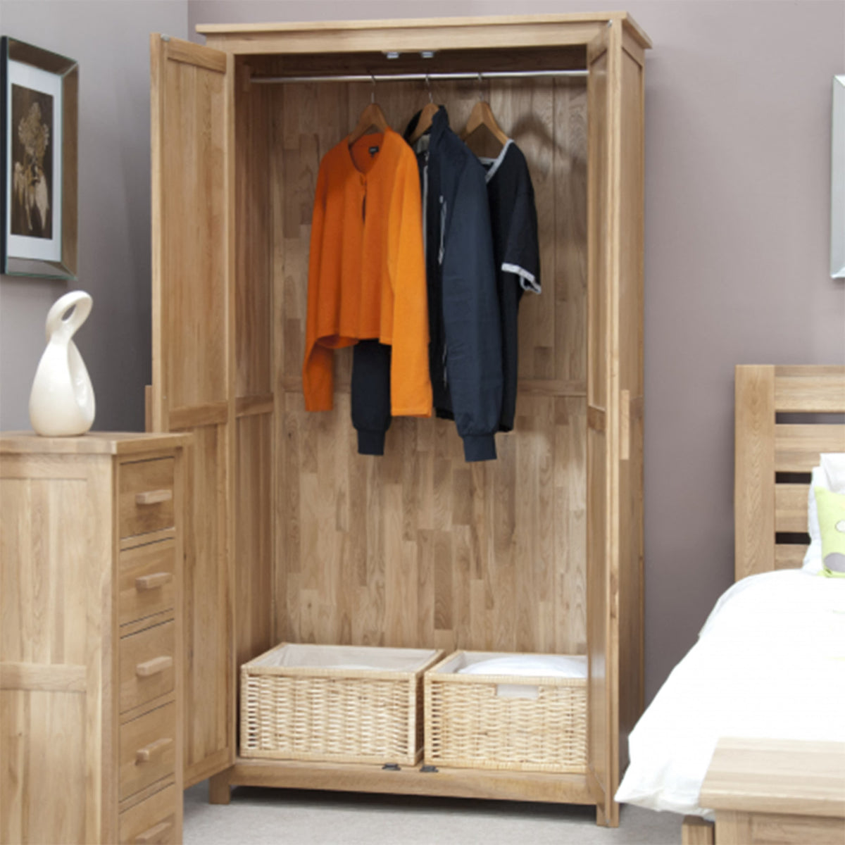 Oak wardrobe with open doors, hanging rail, wicker storage baskets, and wooden drawers