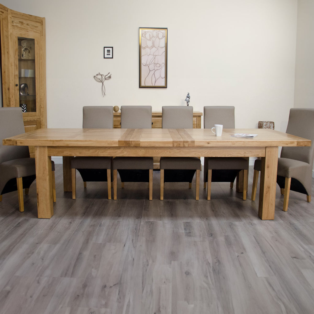 Large oak dining table with eight beige upholstered chairs in a modern dining room