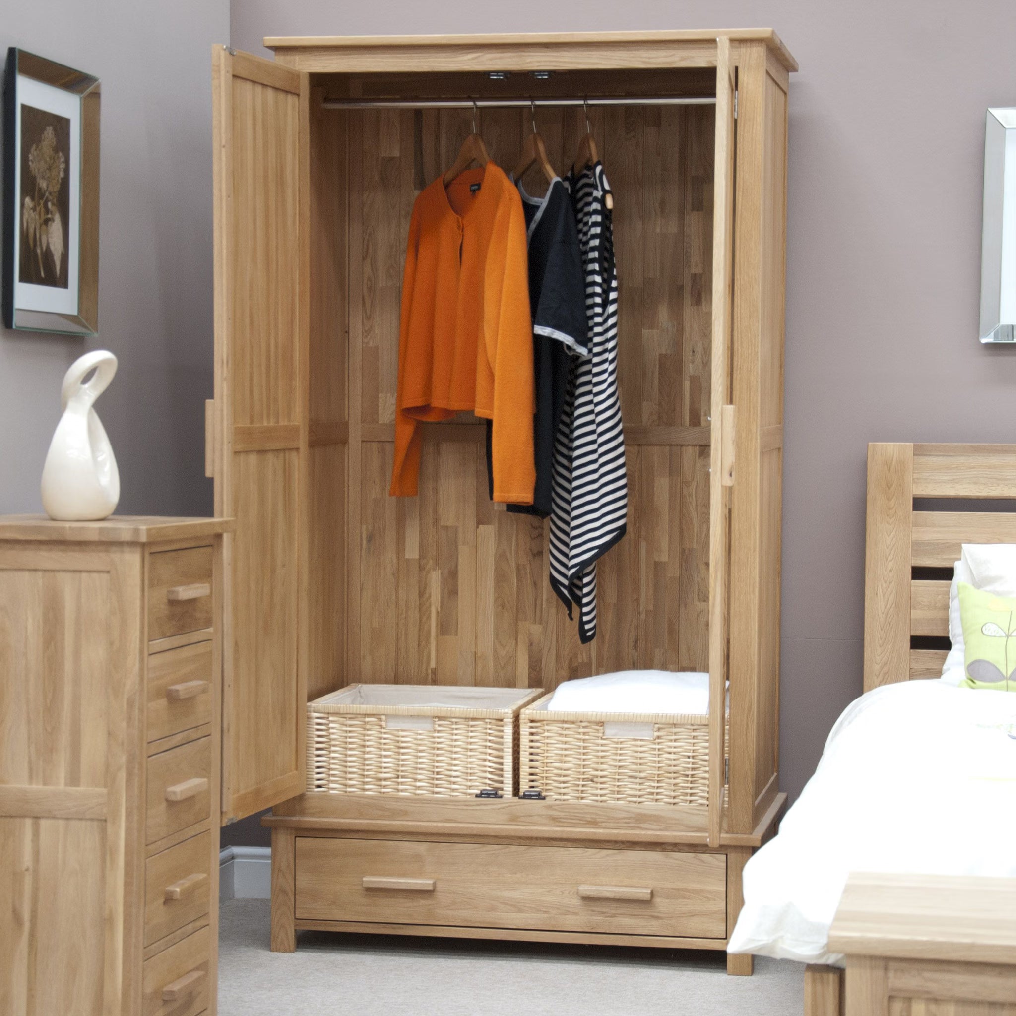 Oak wardrobe with open doors, hanging clothes, wicker baskets, and lower storage drawer