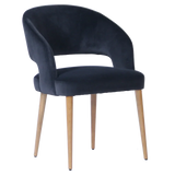 Black velvet dining chair with curved backrest and light wooden legs, front angle view