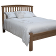 Oak wooden bed frame with slatted headboard and white floral bedding