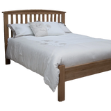 Oak wooden bed frame with slatted headboard and white floral bedding
