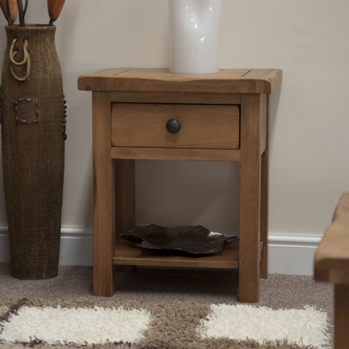 Oak bedside table with drawer and shelf in a living room setting