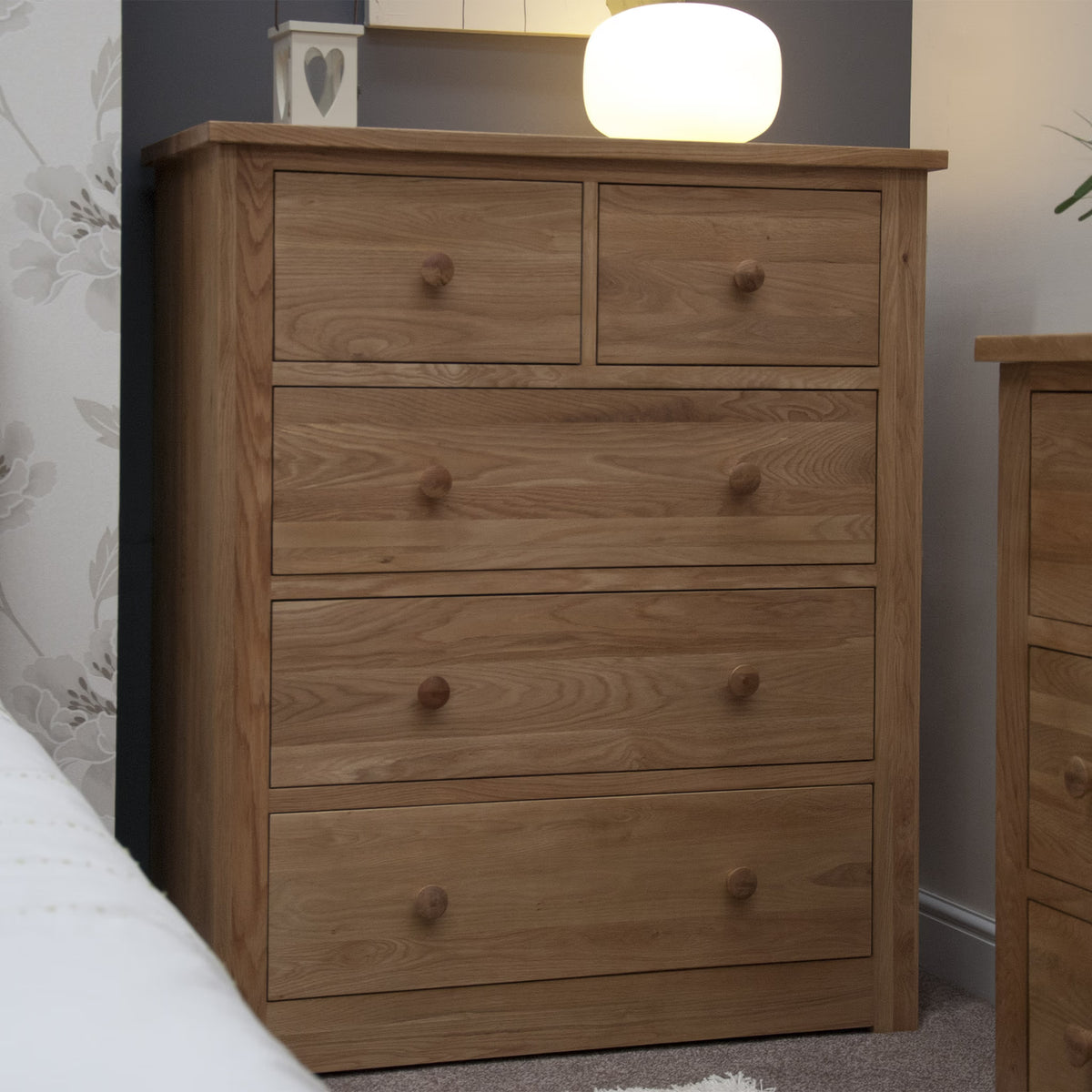 Oak chest of drawers with five drawers in bedroom setting