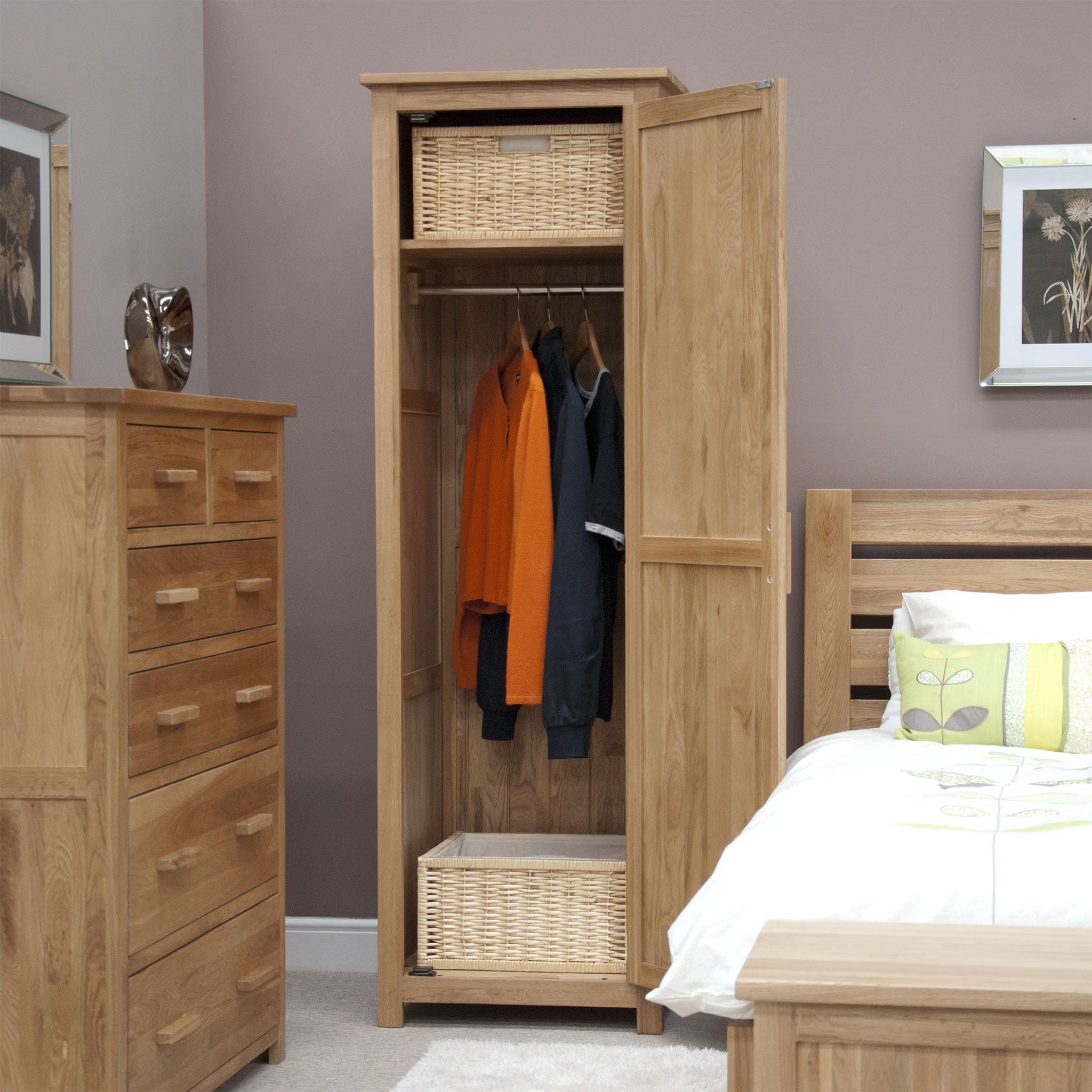 Oak wardrobe with hanging rail, wicker baskets and clothing in modern bedroom setting