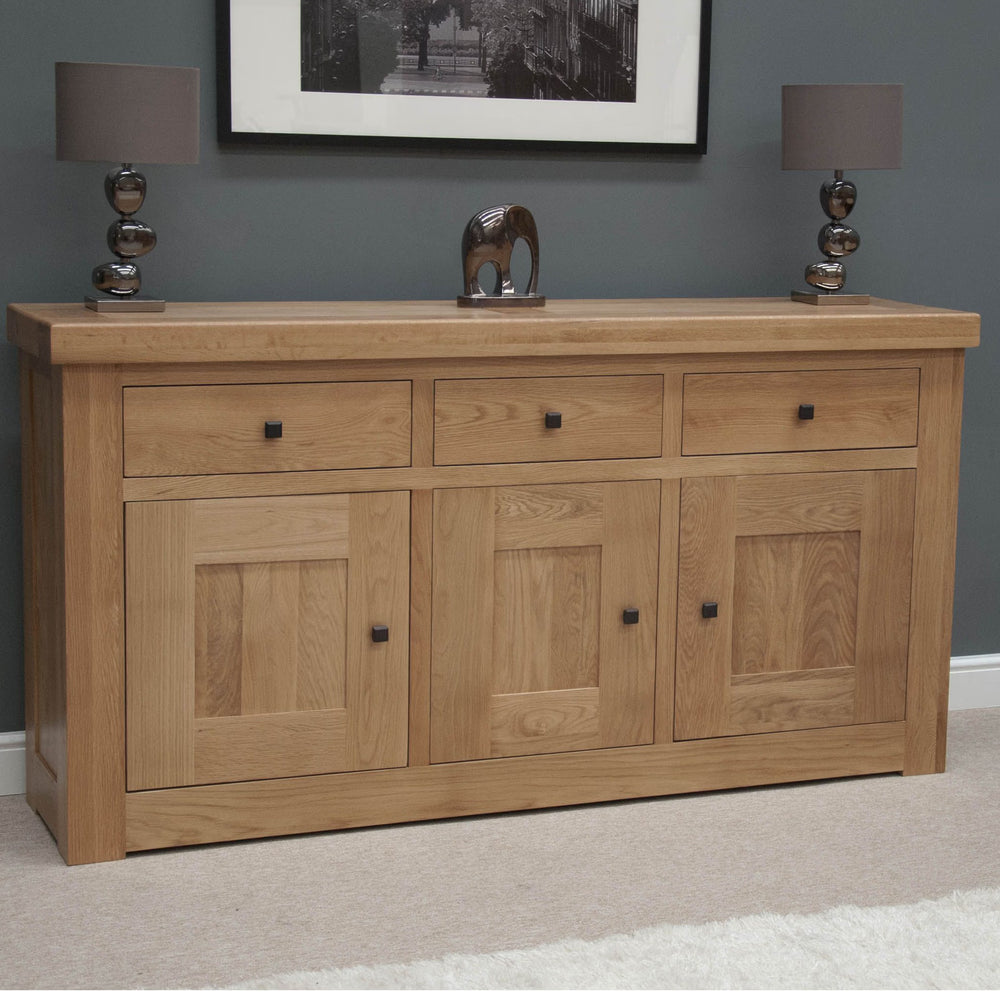 Oak sideboard with three drawers, three doors, black handles, and lamps on top