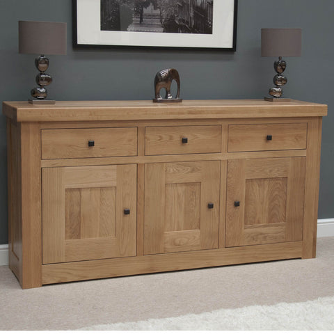 Oak sideboard with three drawers, three doors, black handles, and lamps on top