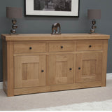 Oak sideboard with three drawers, three doors, black handles, and lamps on top