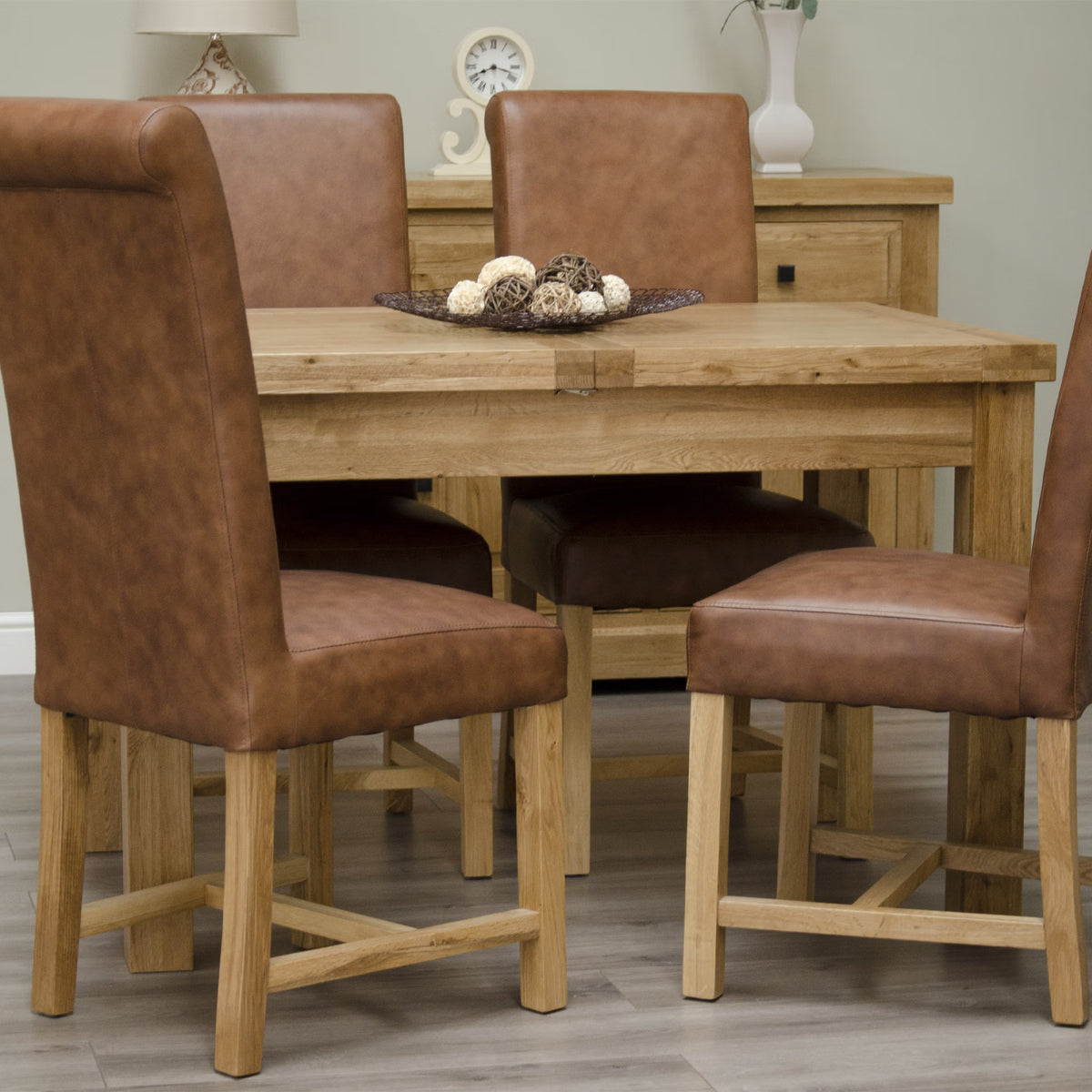 Oak dining table set with four brown faux leather chairs on wood floor