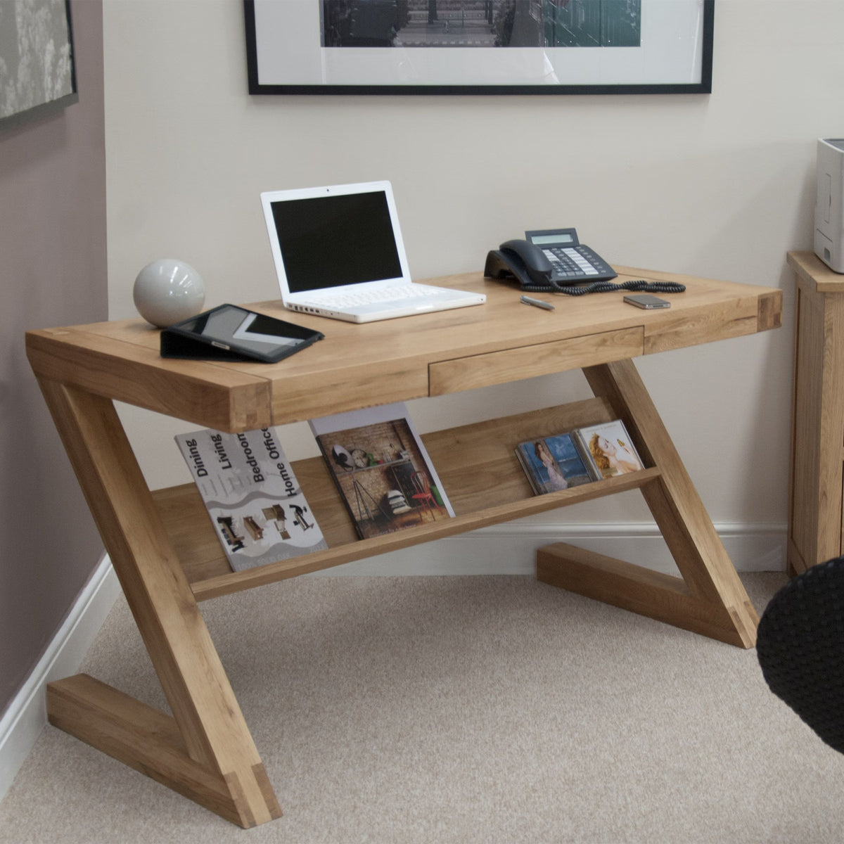 Oak home office desk with slanted legs, open shelf, and workspace essentials arranged on top