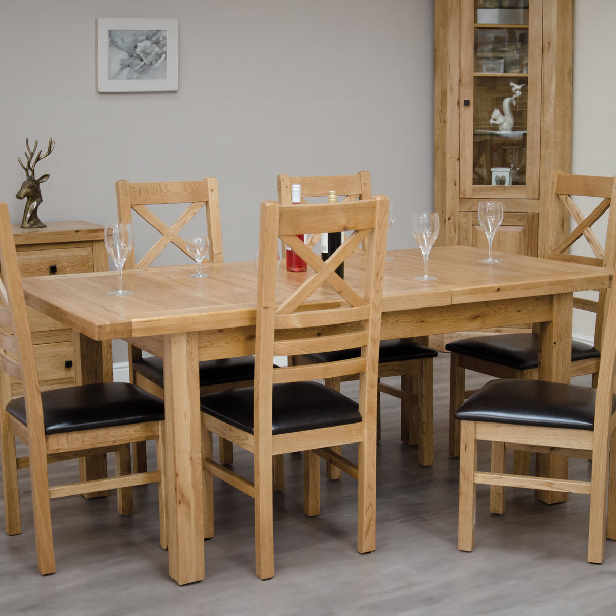 Solid oak dining table set with six black cushioned chairs in modern dining room
