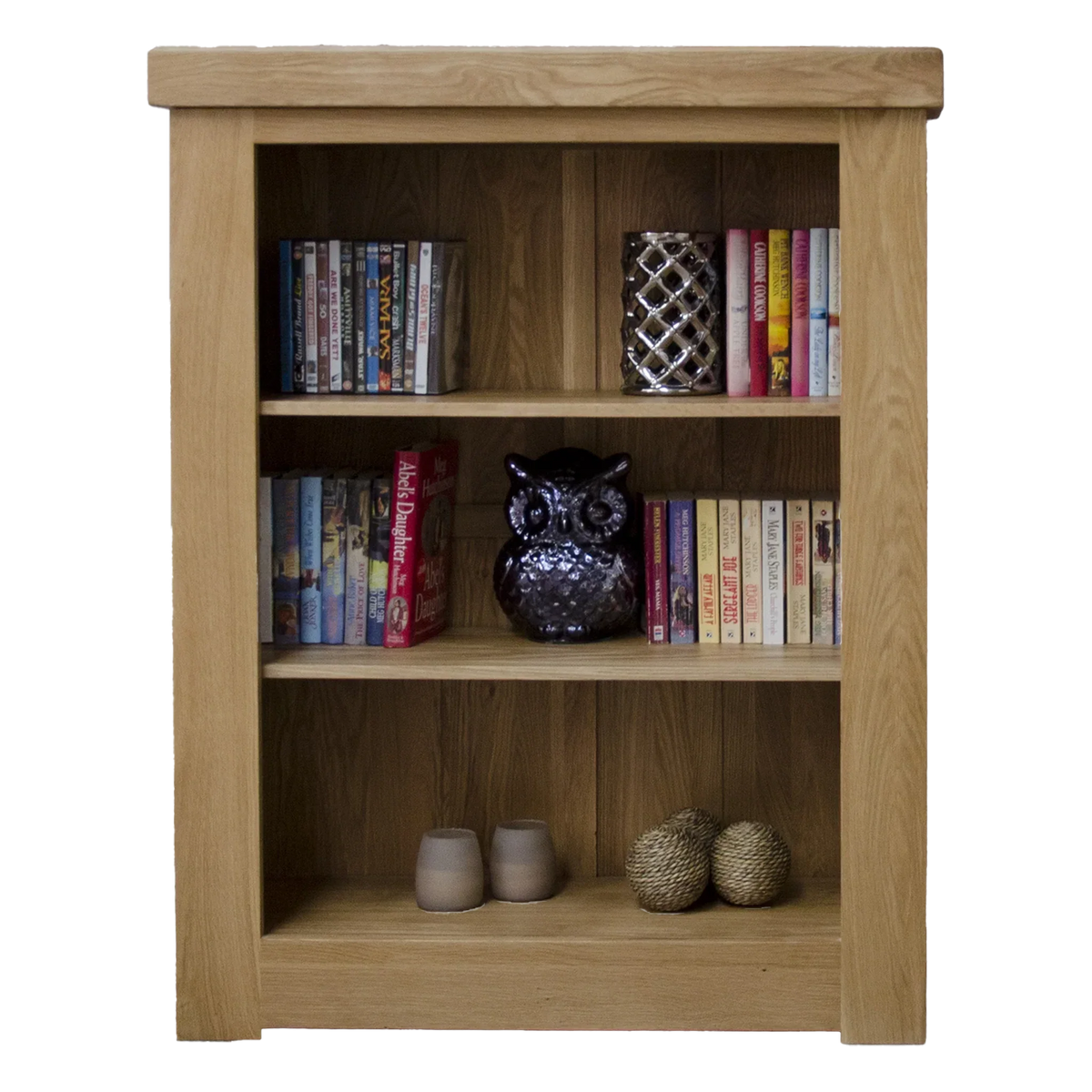 Oak bookcase with three shelves holding books, decorative owl, candle holders, and ornaments