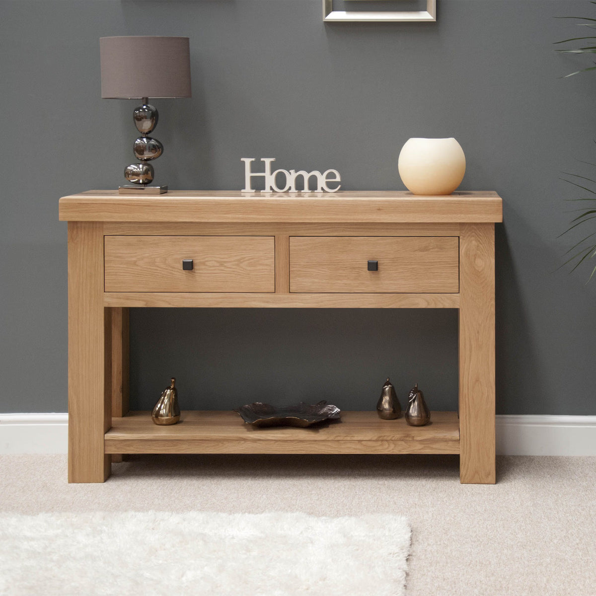 Oak console table with two drawers, lower shelf and decorative items in modern living room