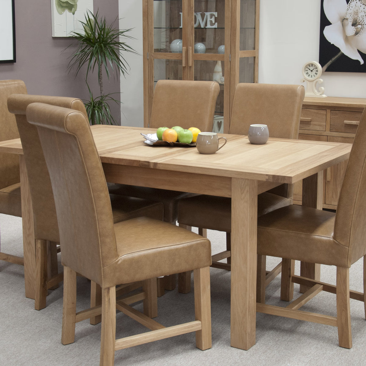 Oak dining table set with six tan leather chairs in a modern dining room
