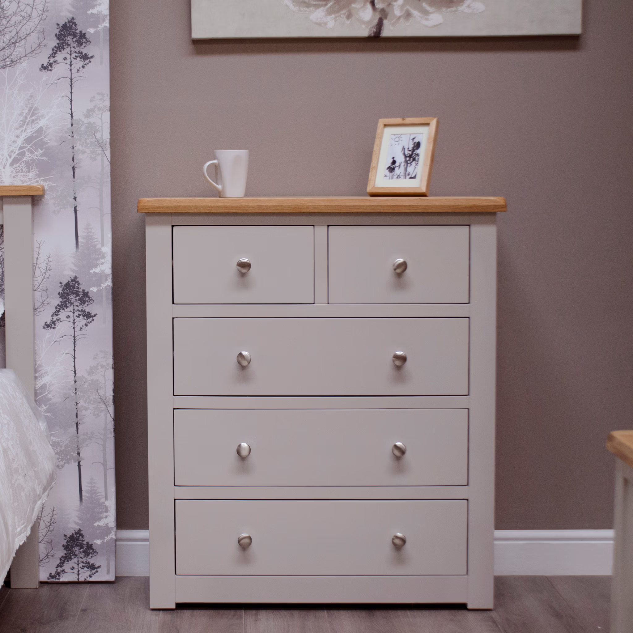 Five drawer chest in light grey with wooden top in bedroom setting