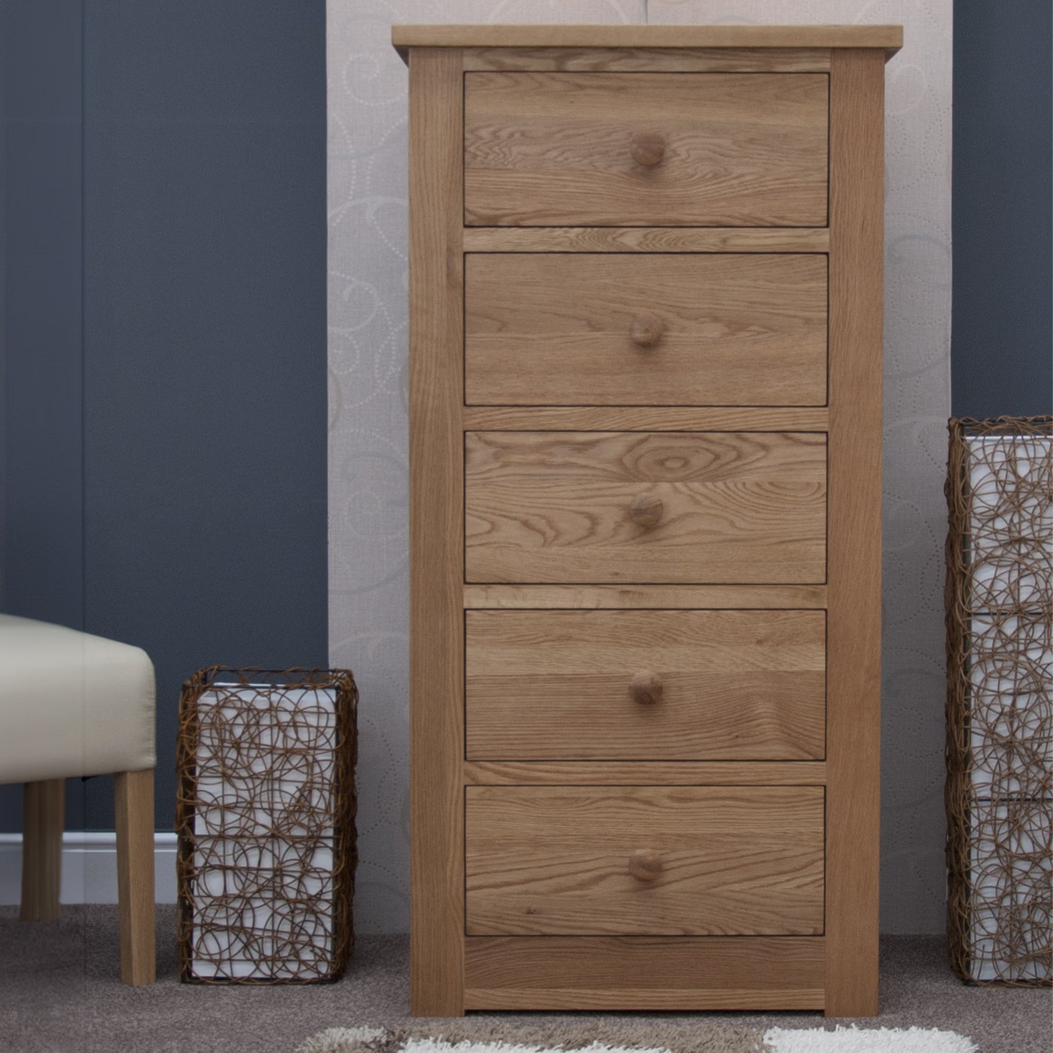 Oak chest of drawers with five drawers in bedroom setting on carpeted floor